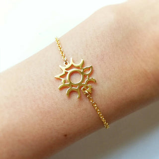 Zoom up on a model's wrist with gold sun motif bracelet.