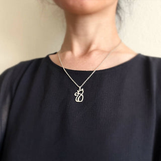 A model is wearing silver cat necklace on navy top.