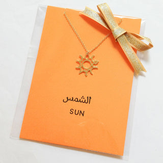 Wrapping sample photo of sun necklace.  Set on orange card in clear sleeve with gold ribbon.